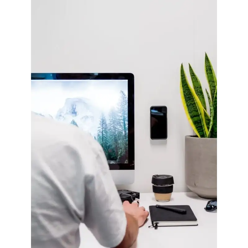 Person bruker datamaskin på minimalistisk skrivebord med Quad Lock Adhesive Wall Mount
