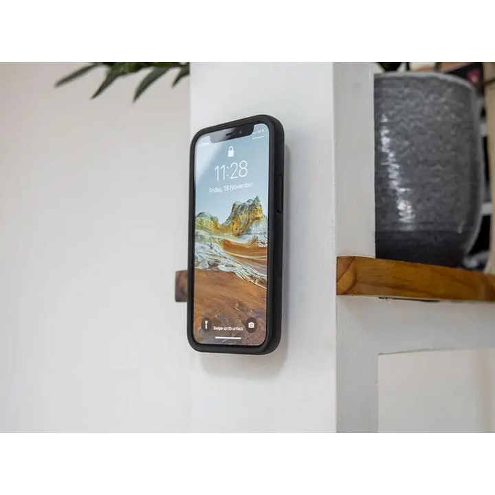 En svartkledd smarttelefon med låseskjerm og ørkenlandskap bakgrunn på Quad Lock Adhesive Wall Mount