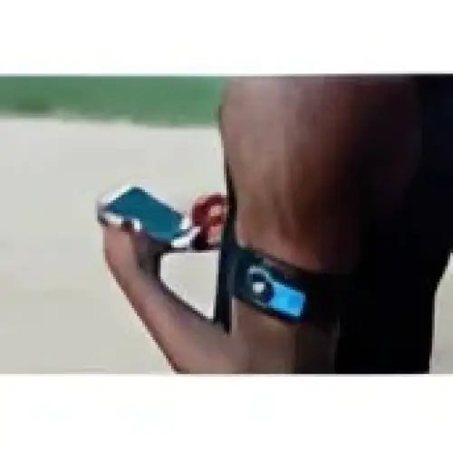 Fitness tracker armband på en persons arm sammen med en smartphone for trening