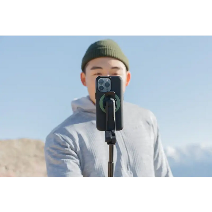 IPhone i svart etui montert på selfie-stang med grønn MagSafe-tilkobling for Quad Lock Tripod Selfiestang